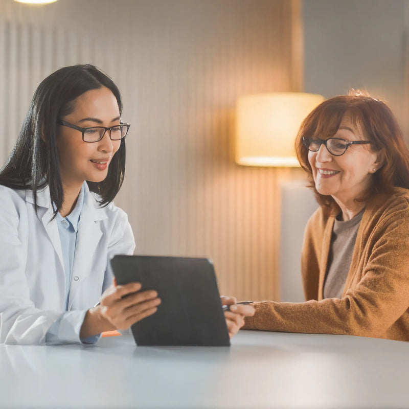 Doctor showing test results on a tablet to an elderly patient during a consultation.